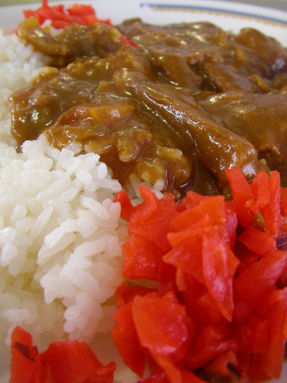 a plate of food has rice, meat and red peppers