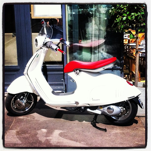 a white motor scooter parked outside of a store