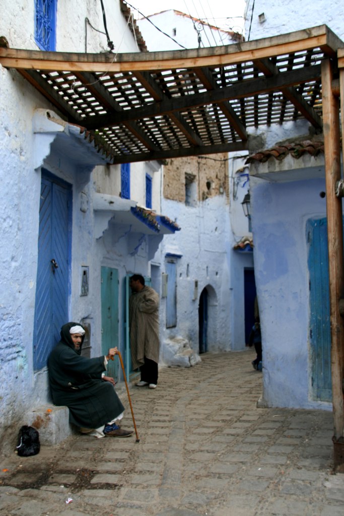 people walking on a street near blue buildings