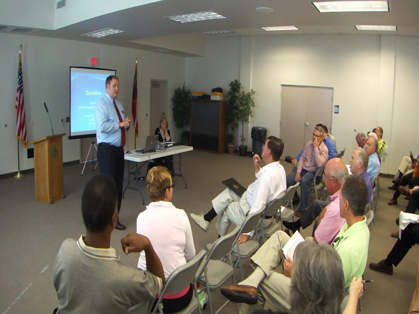 a group of people sitting on the chairs at a meeting in a room