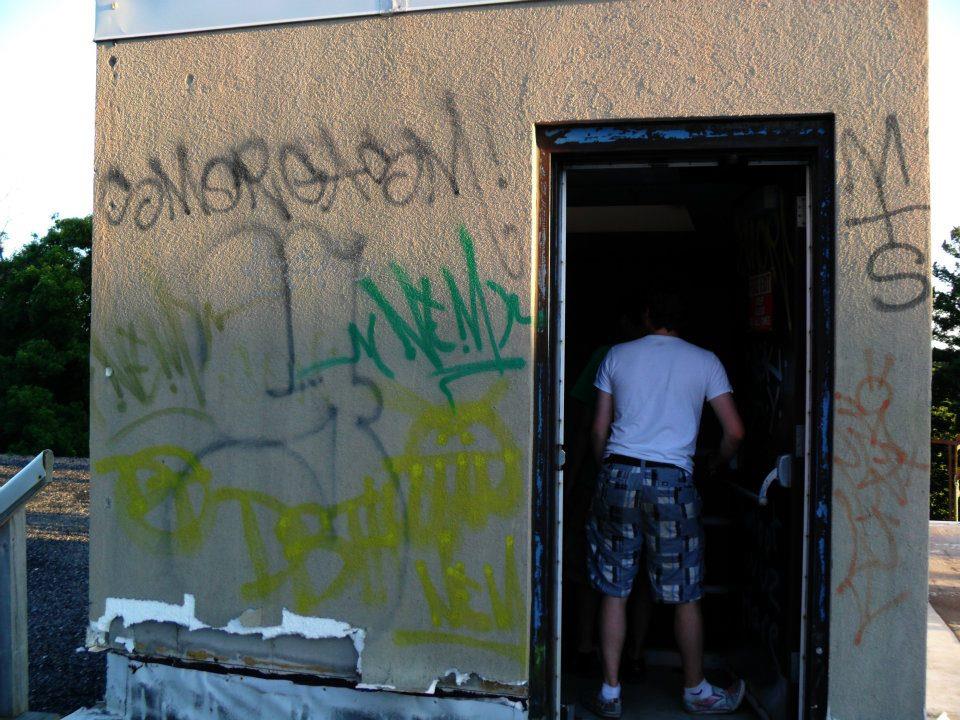 a man walking into an open doorway covered in graffiti