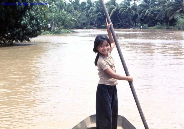 little girl standing in the front end of a boat holding a pole