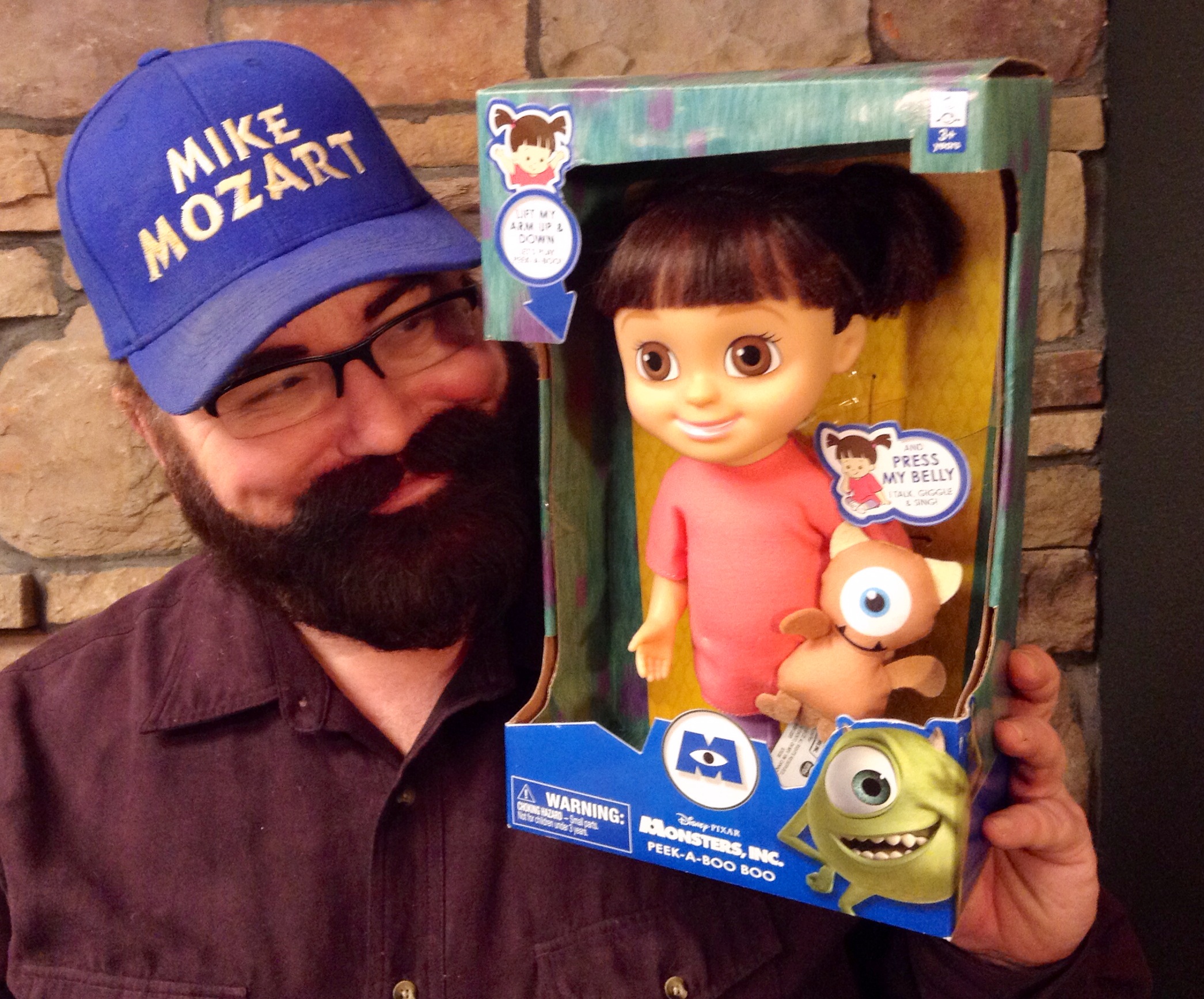 a man with glasses holding a new in package doll