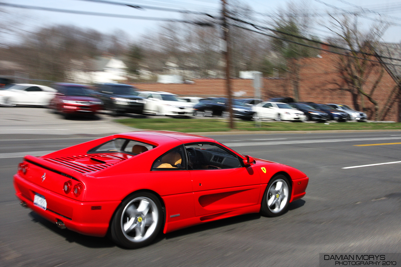 red sports car driving down the road by the parking lot