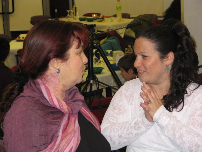 two women sitting at a table with their hands clasped together