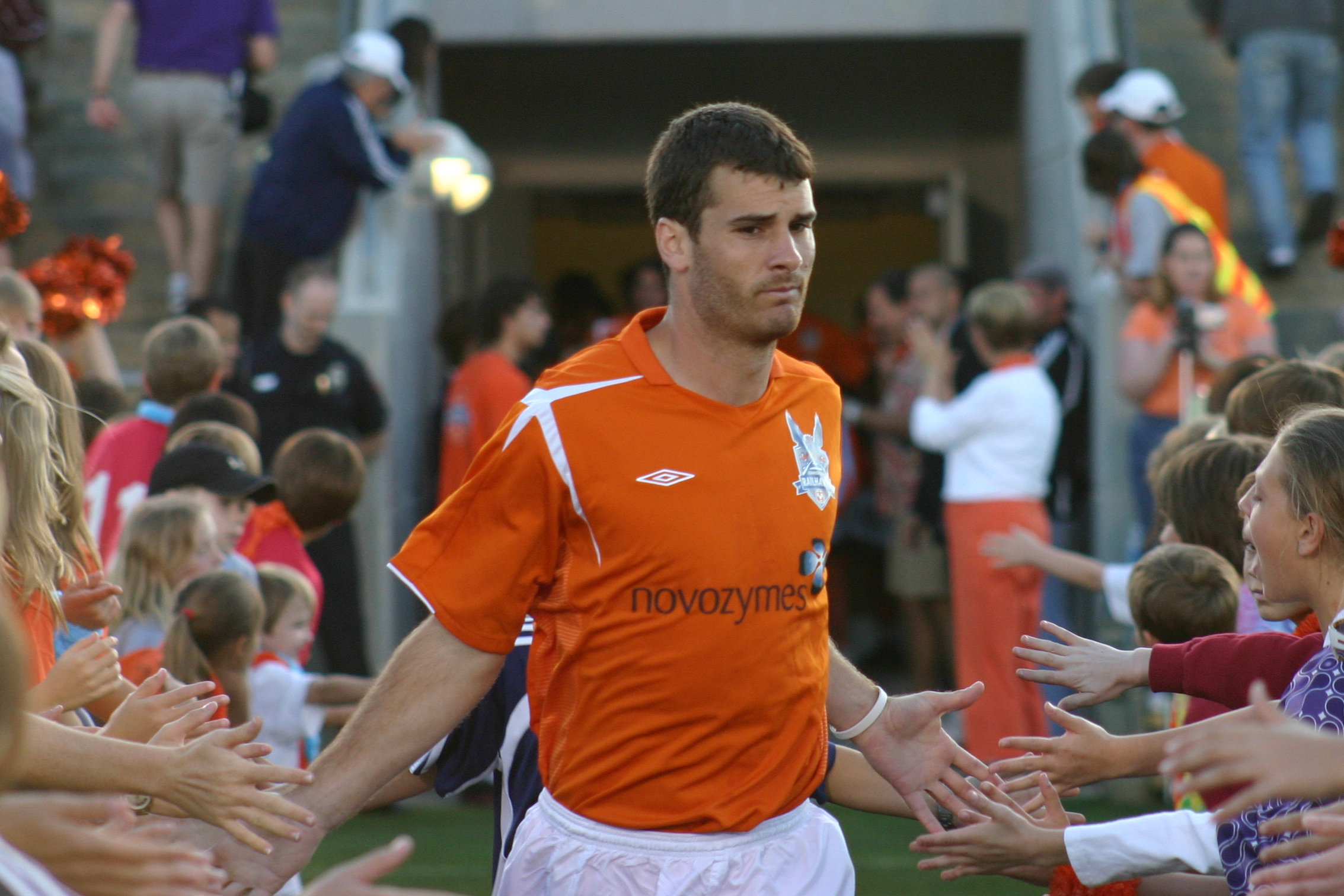 a man wearing an orange uniform standing in front of lots of people