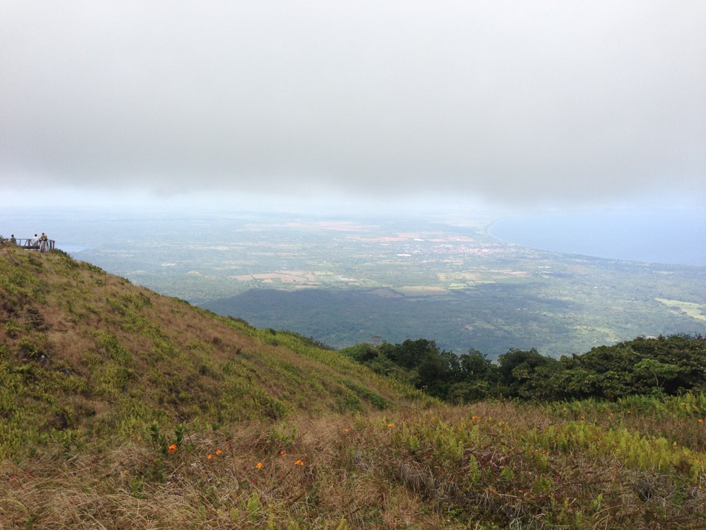 the foggy scenery of a grassy mountain peak overlooks the distant land area