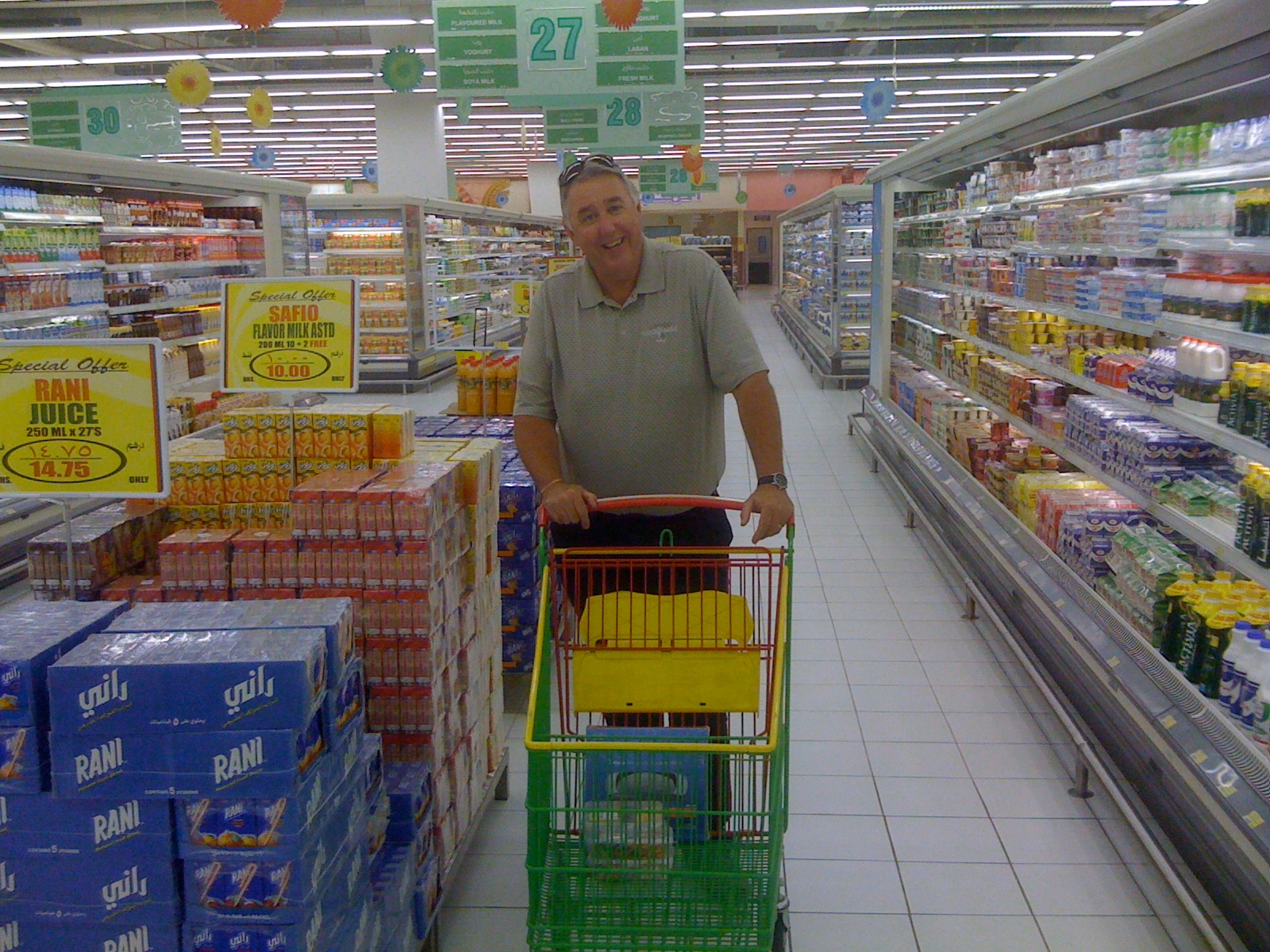 a man in a supermarket store hing a shopping cart with drinks inside