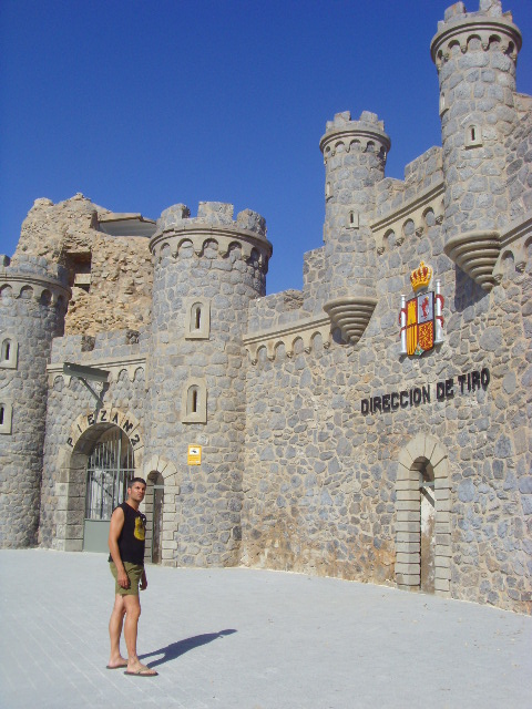 a woman stands in front of an old stone castle