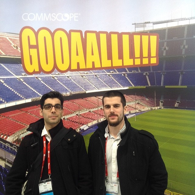 two men standing in front of a large stadium sign