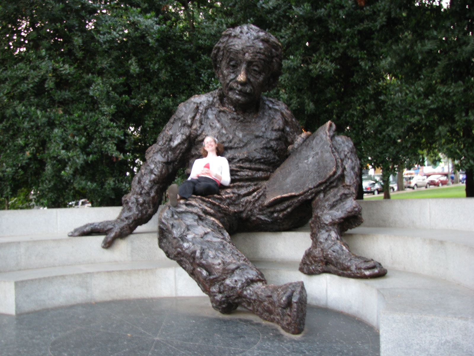 a woman sits in front of a statue