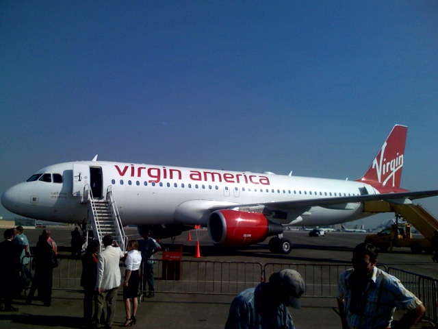 a virgin america plane at an airport with a crowd of people boarding it