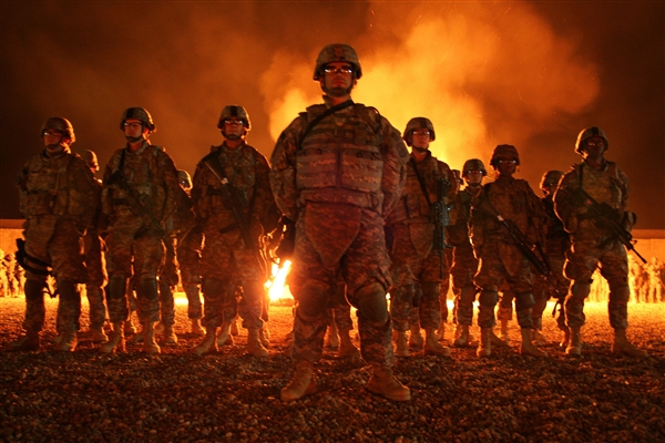 a man in military camouflage stands in front of a group of men