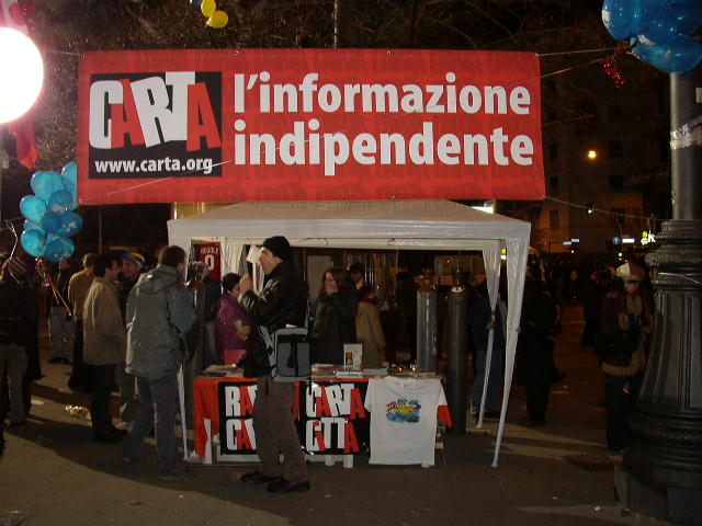 a small stand with signs and balloons at night
