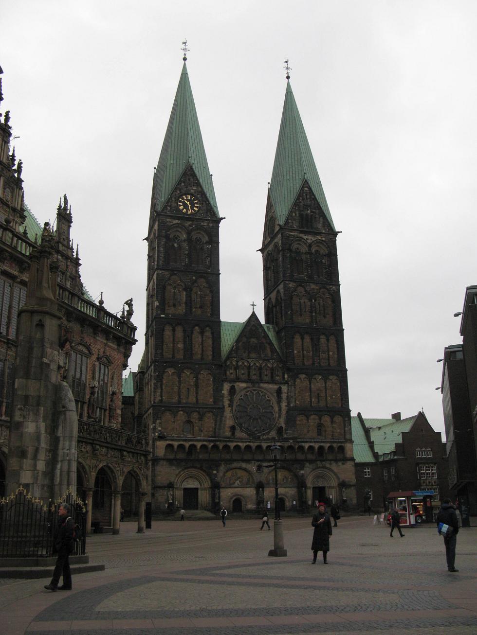 a stone cathedral with steeples stands in a large courtyard