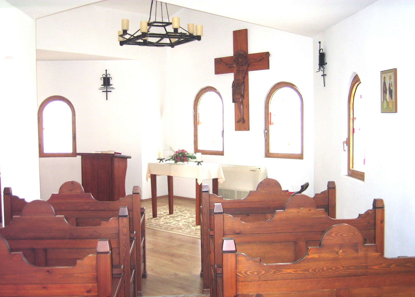 the interior of a small chapel with pews and benches