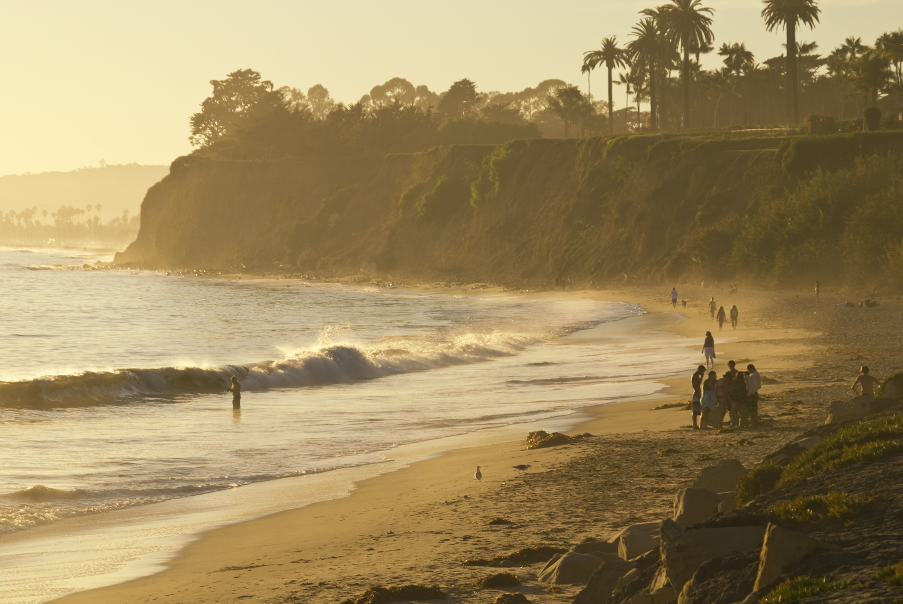 there are people walking down the beach in the sunset