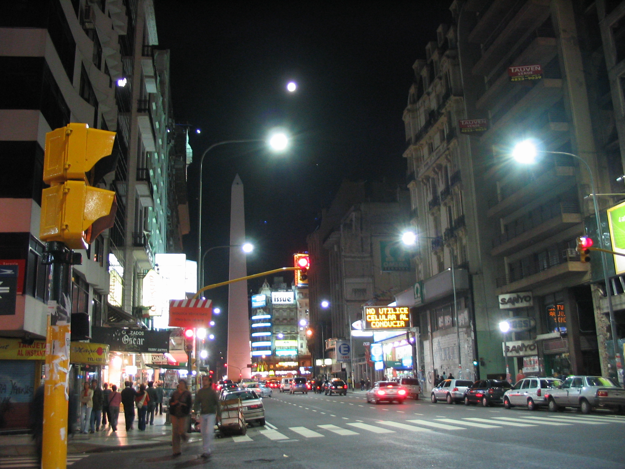 a busy city at night with people crossing the street