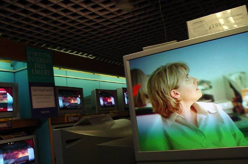 an airport television on display with a woman sitting on a chair