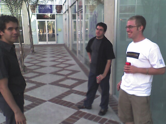 three men standing in a street, all talking to each other