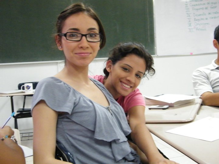 two people in a classroom, one girl is sitting down