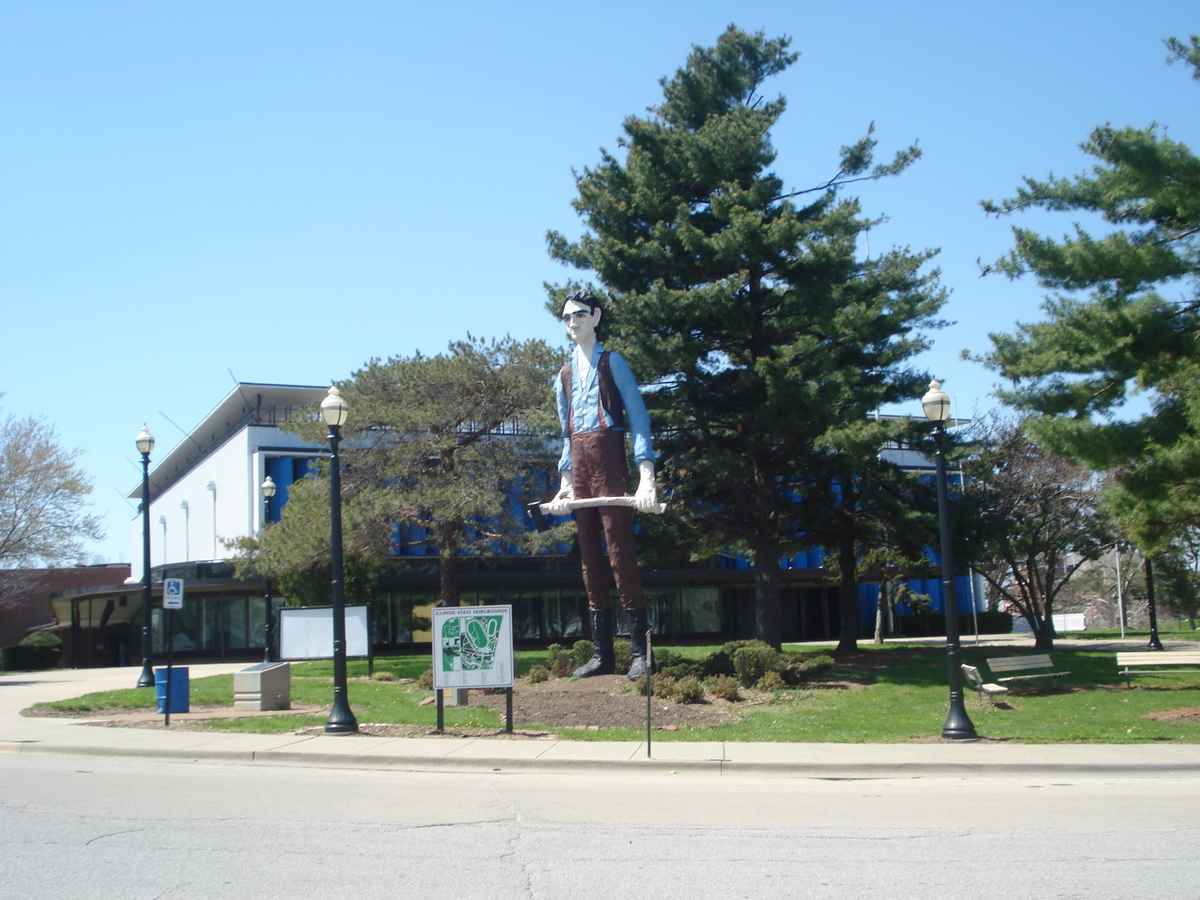 the street has a blue building behind the large statue of a person