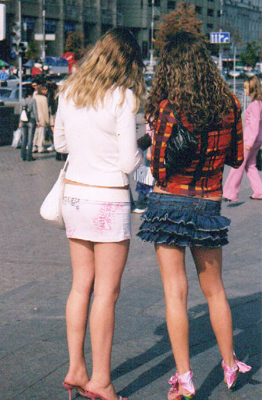 two girls in high heels and skirts on a sidewalk