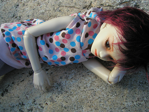 doll lying on sidewalk with polka dotted shirt and legging