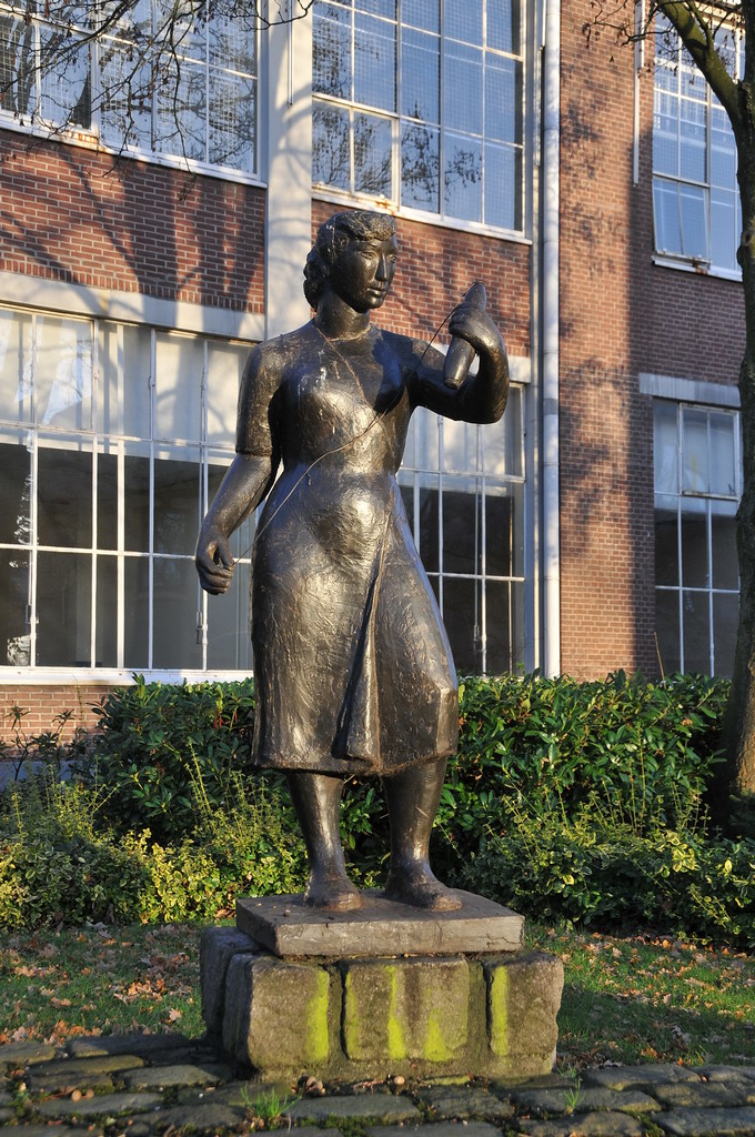a metal statue stands in front of a tall brick building