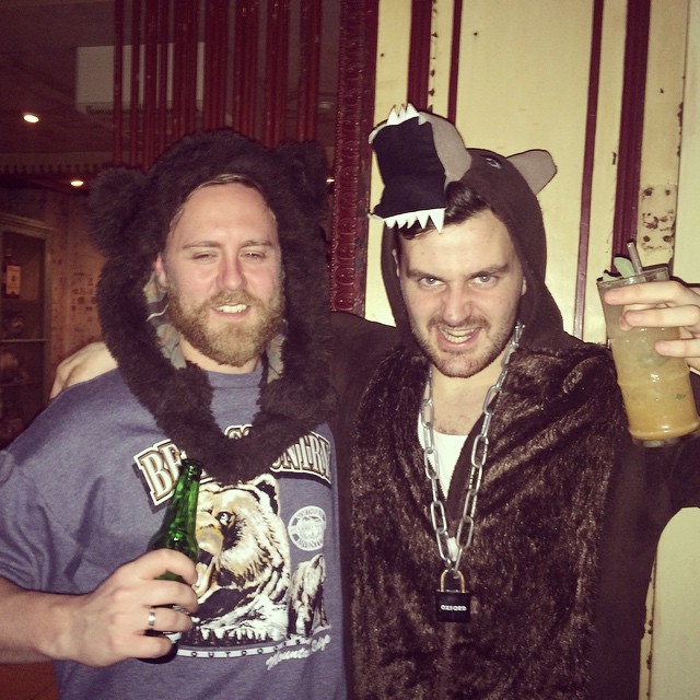 two men dressed up in costume holding beverages