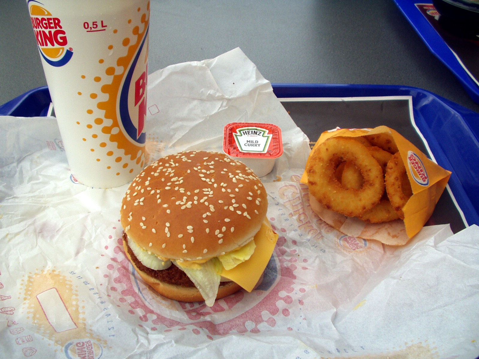 a tray holding an odd burger with onion rings, coffee and a doughnut