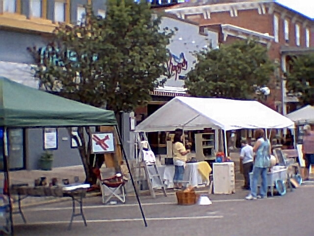 people are walking around in a parking lot under tents