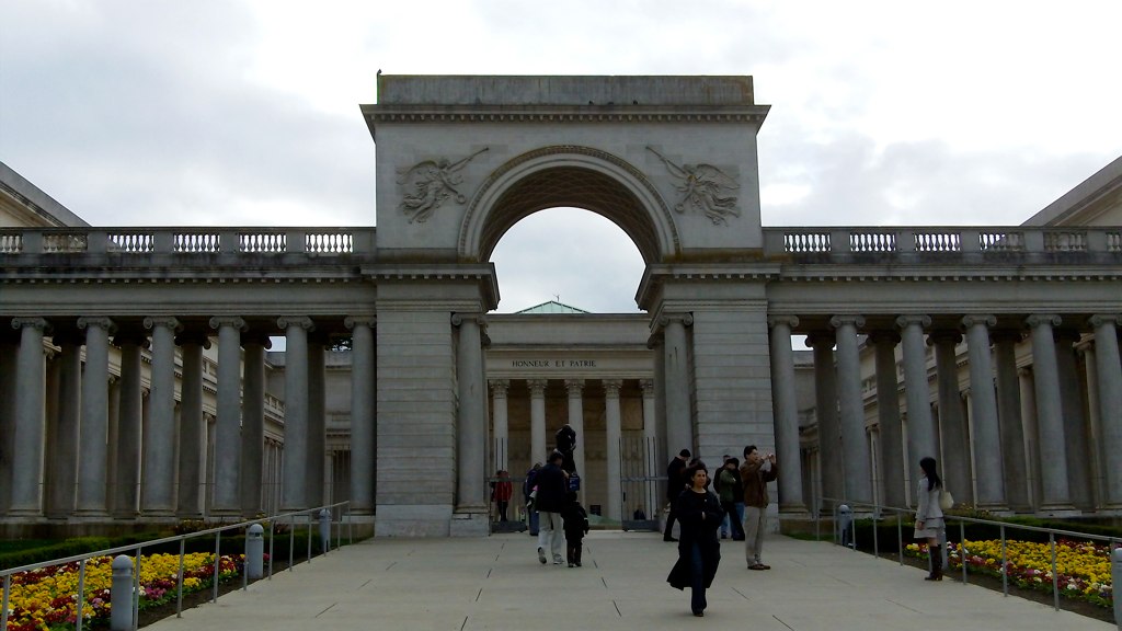 people walking towards an archway in the middle of a large courtyard