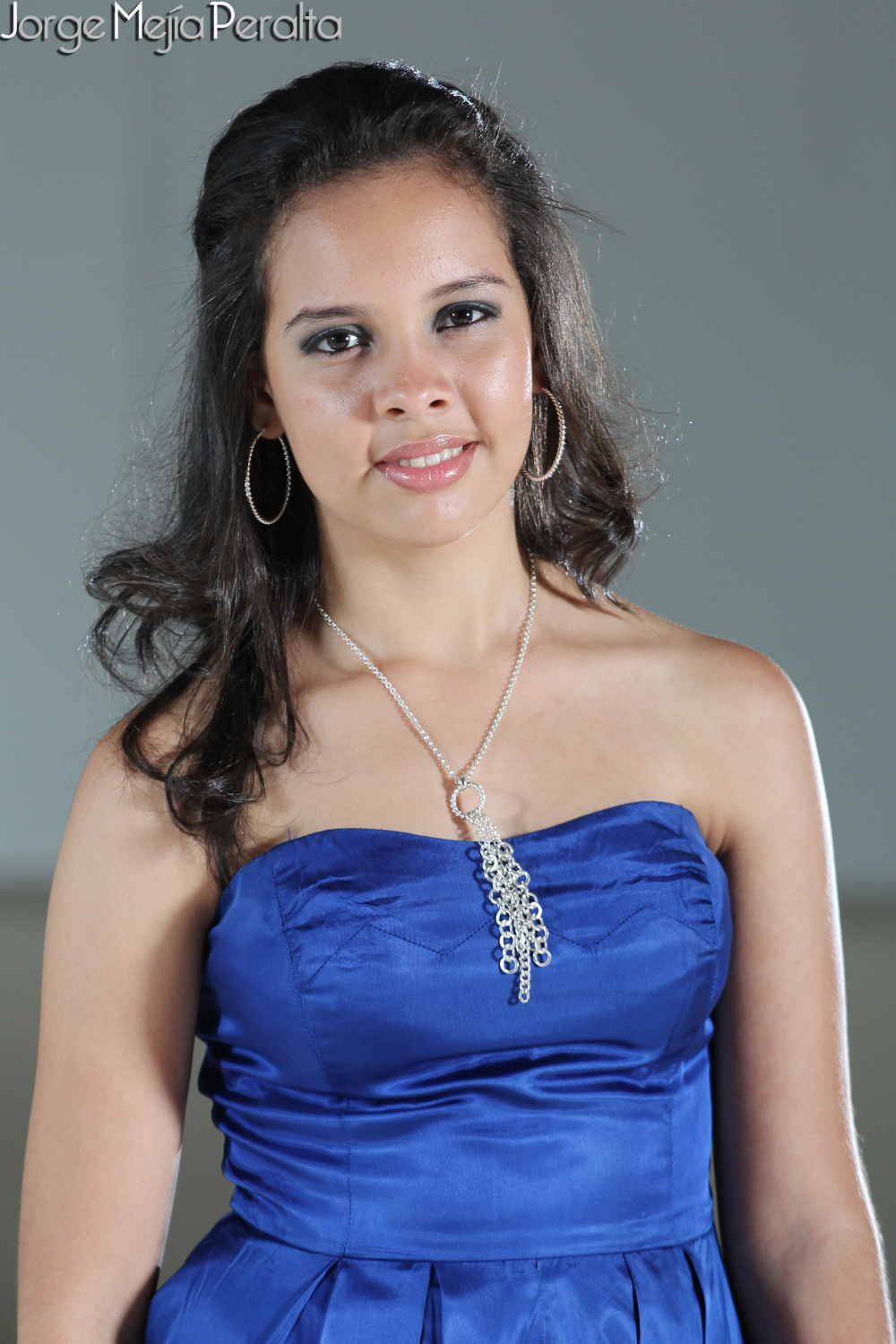 a beautiful young lady with long dark hair and big earrings