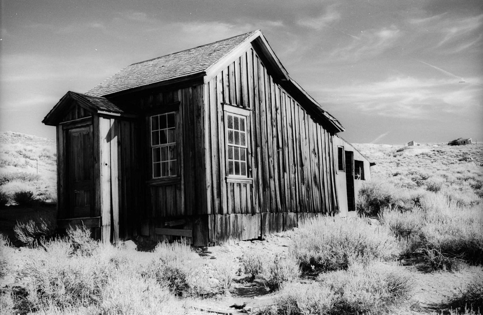 a building sits on a remote area of dry grass and scrub brush