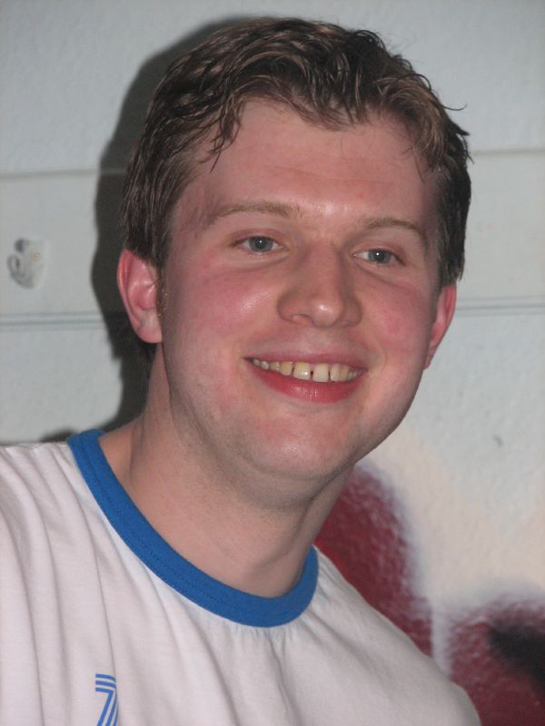 a man with brown hair wearing a white shirt smiling
