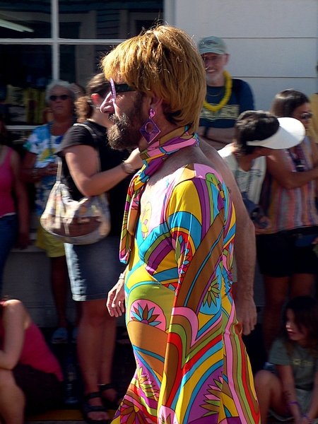 man in multi colored costume walking in front of crowd