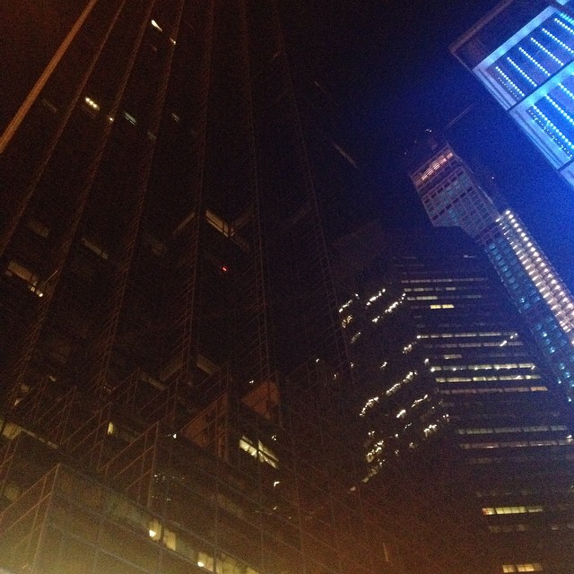 view of skyscrs in the evening at night, with bright lights