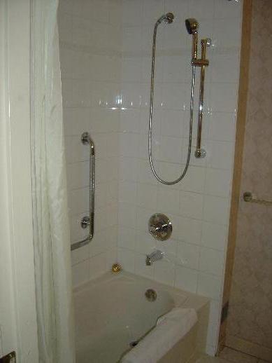 a bath tub with a glass door and towel rails on the wall