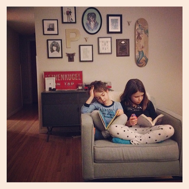 two girls sitting on a couch playing with their books