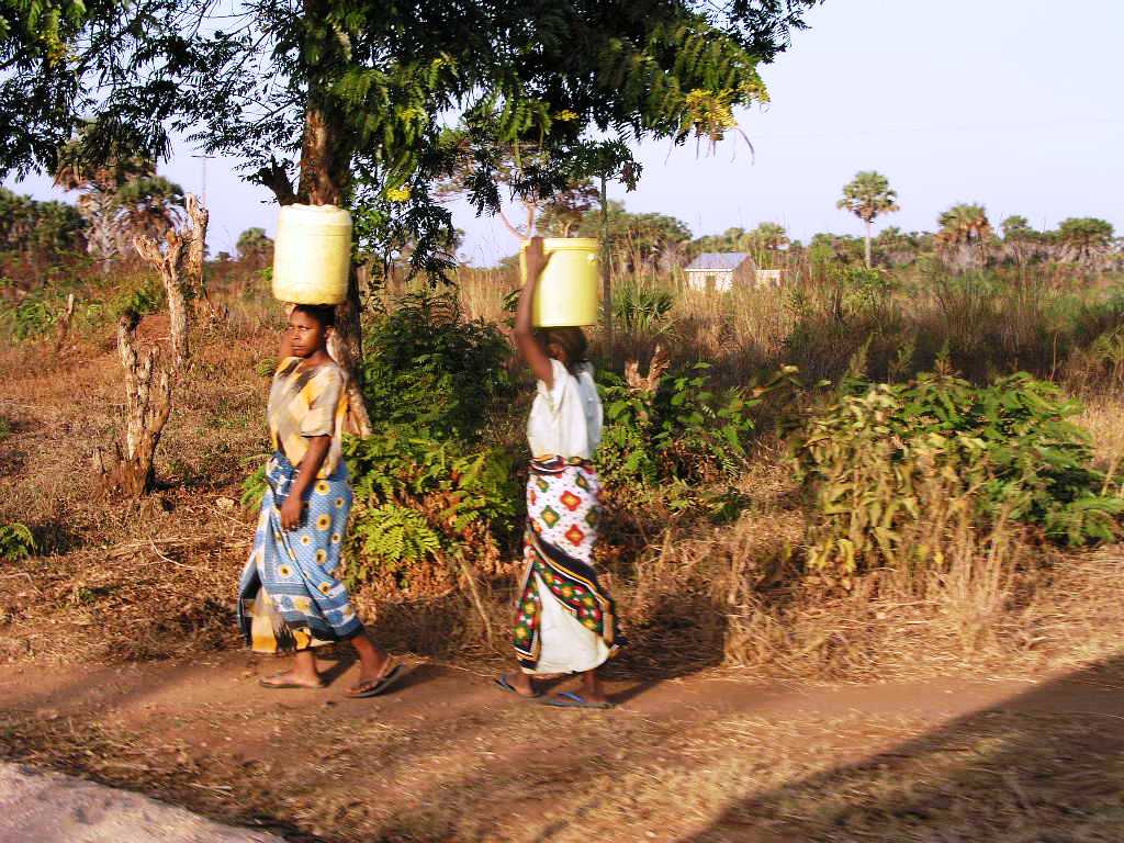 two women carrying containers of water on their heads