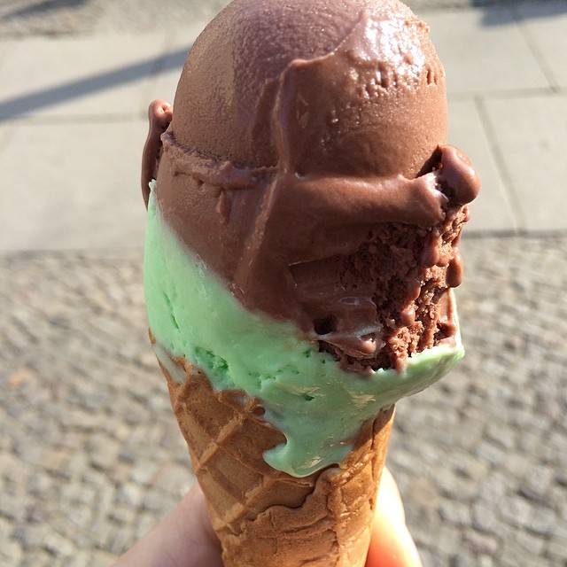 a person holds a ice cream cone with chocolate and mint