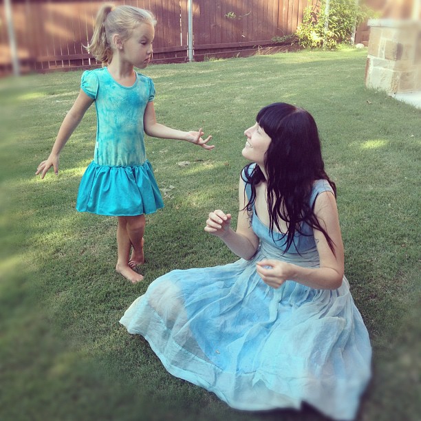 two girls in dresses playing outside on the grass