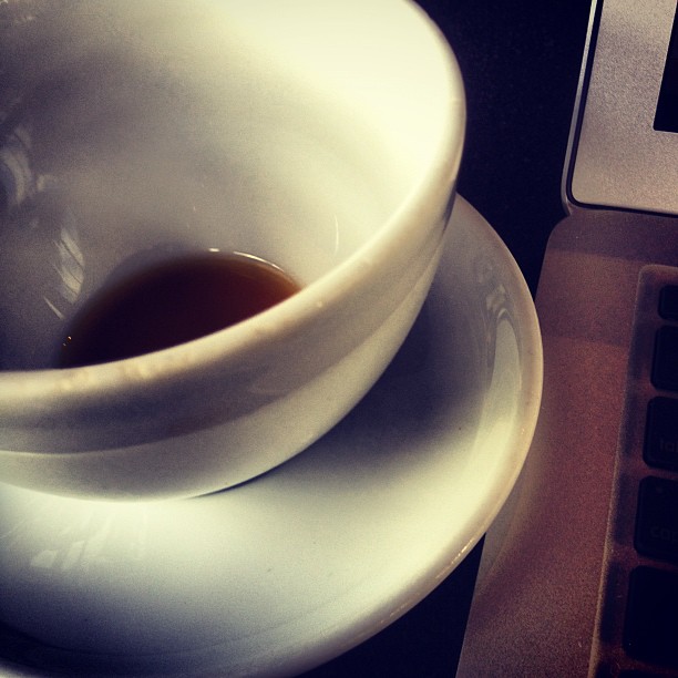 a coffee cup next to an open laptop computer