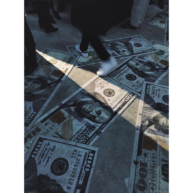 a man standing on a pile of dollars with his shadow cast