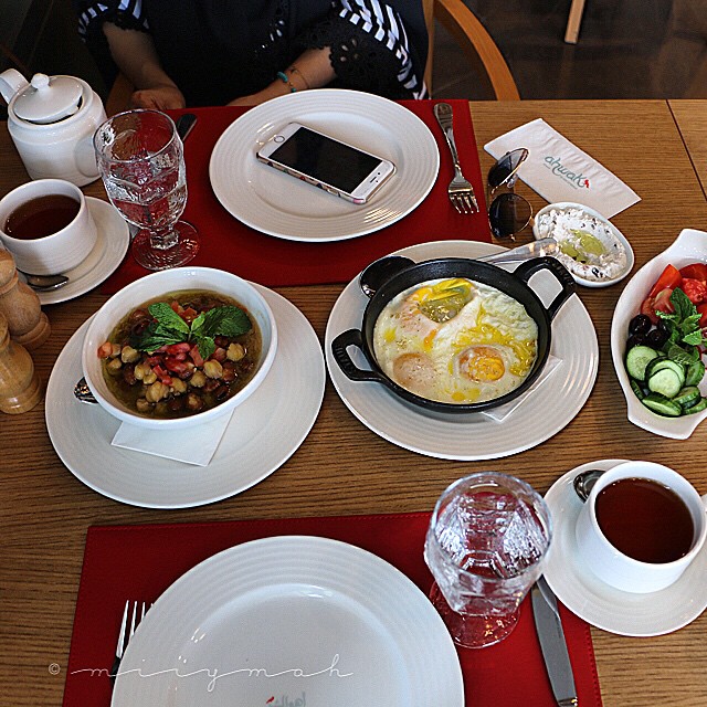 a table topped with lots of white plates filled with food