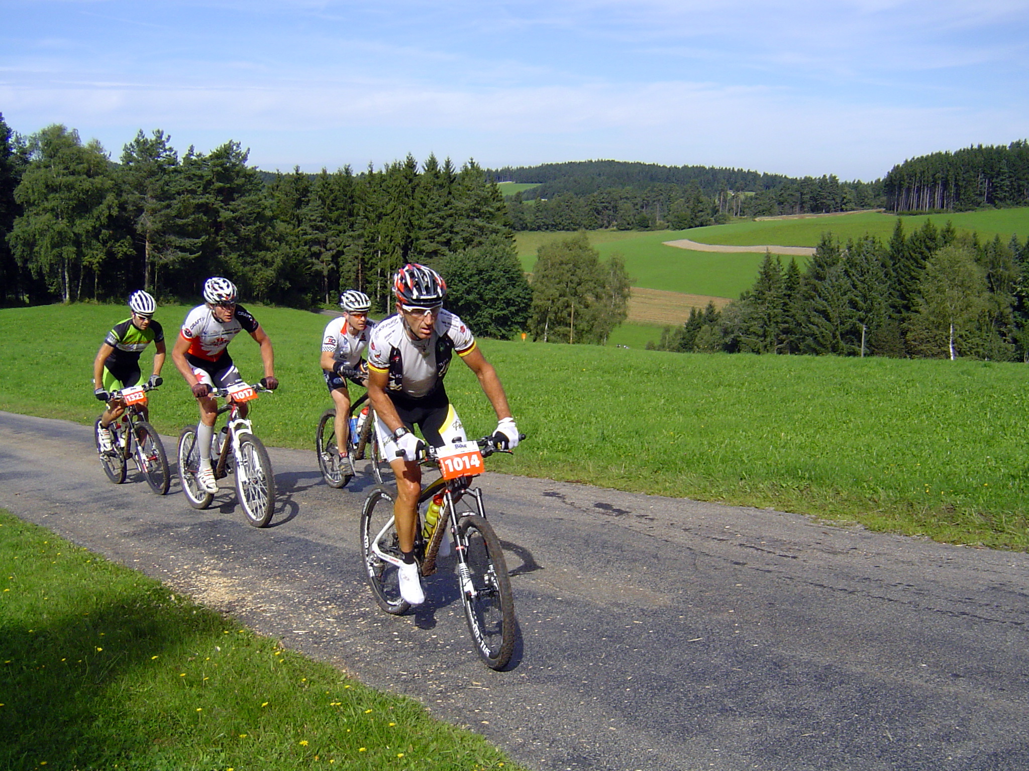 four people riding mountain bikes down a paved trail