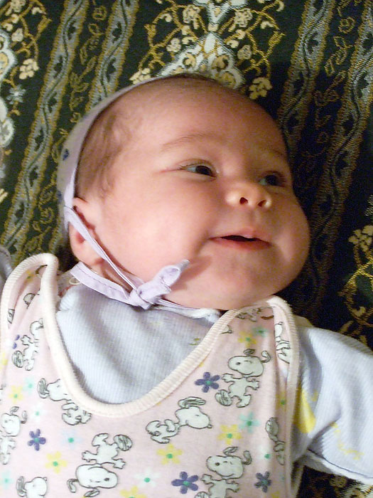 baby in bib laying on patterned bedding