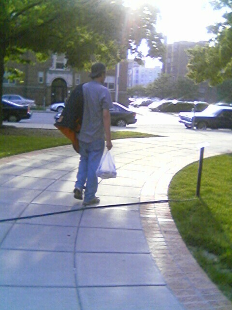 a man carrying two shopping bags walking down a sidewalk