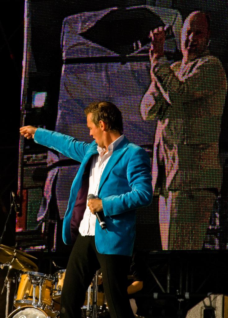 a man wearing a jacket is doing a fist - bump on stage